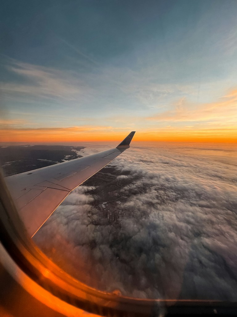 Flugzeugflügel im Sonnenuntergang über den Wolken